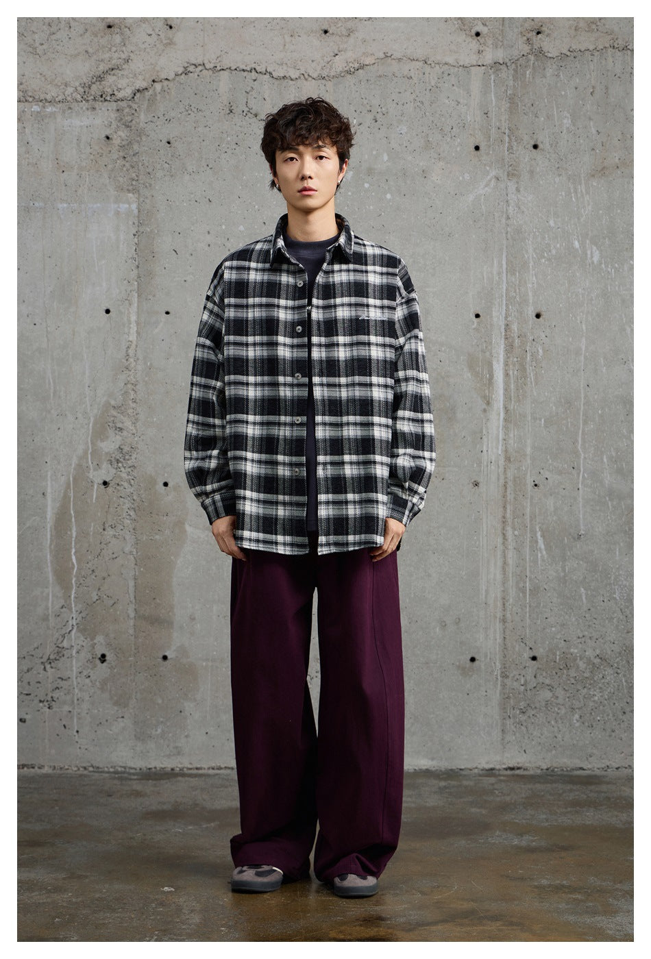 Model wearing a black-and-white plaid button-up shirt over a dark tee, shown from the front.