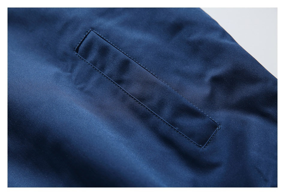Close-up of a narrow diagonal pocket on smooth navy jacket fabric.