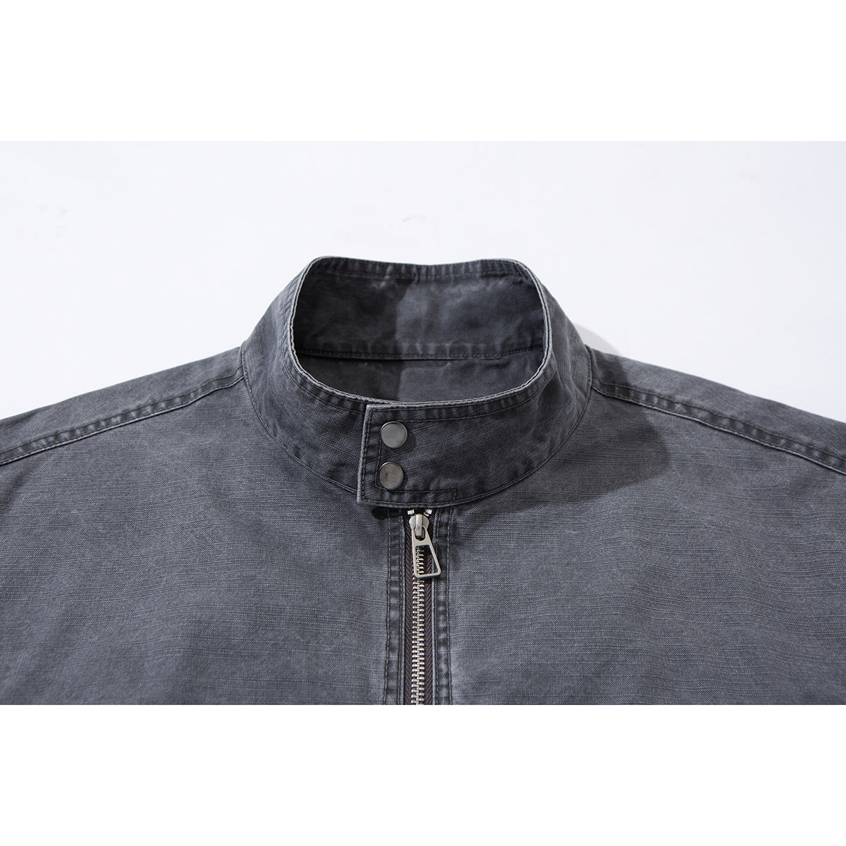 Close-up of a charcoal-gray jacket’s stand collar, snap buttons, and front zipper.