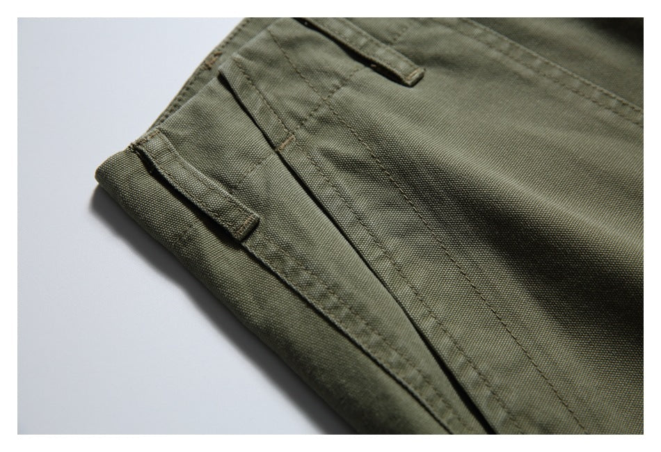 Close-up of olive trousers showing stitched fabric tabs and a long seam.