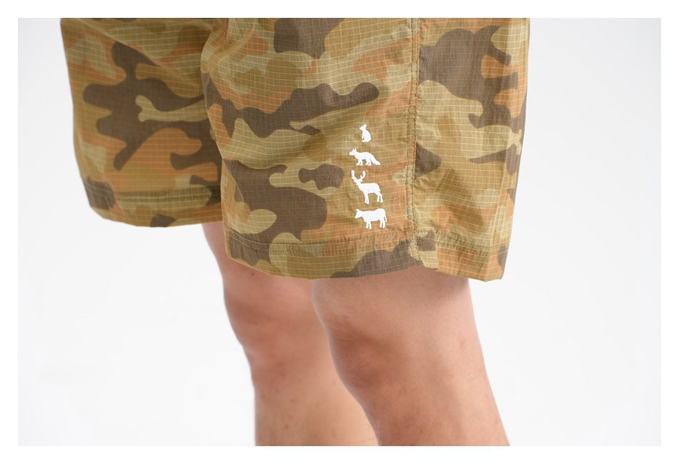 Close-up of camouflage shorts with a vertical row of small white animal silhouettes near the hem.