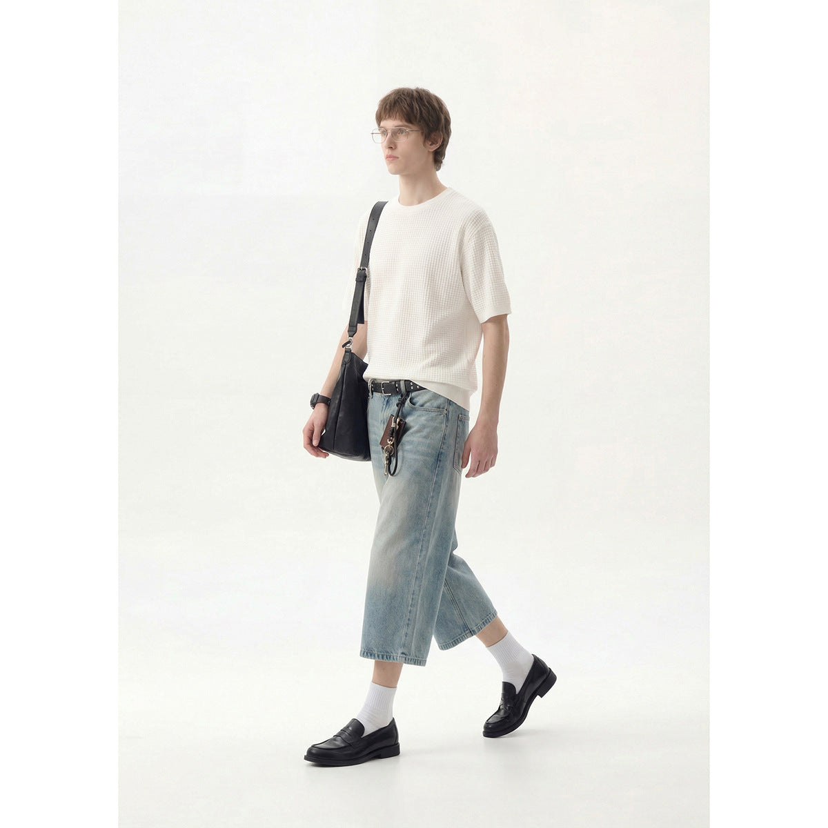 Model wearing an off-white textured short-sleeve crew-neck shirt with light cropped jeans and black loafers.