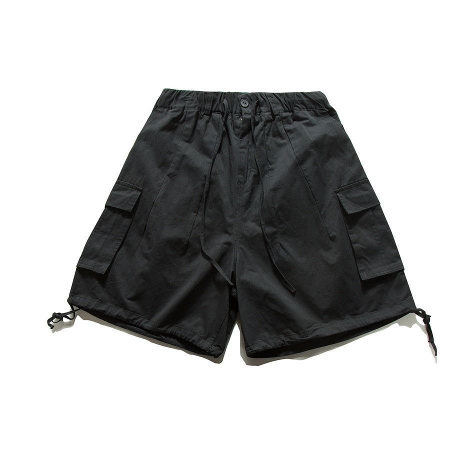 Black cargo shorts with elastic drawstring waist, side flap pockets and hem drawcords, flat lay front view