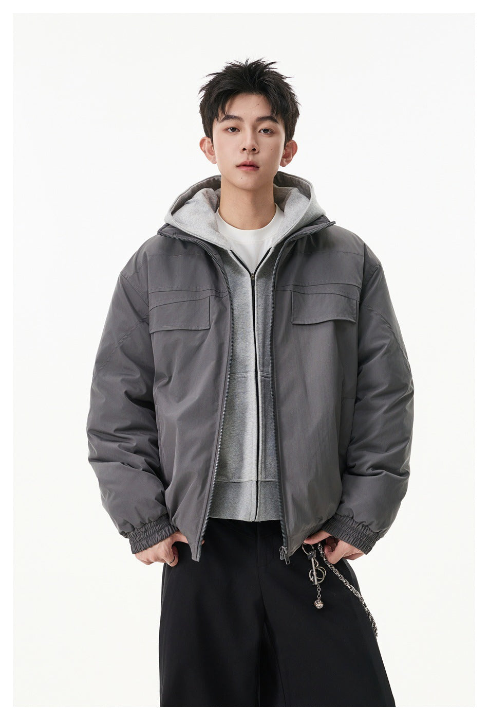 Closer front view of a model wearing a gray zip jacket with flap chest pockets over a gray hoodie.
