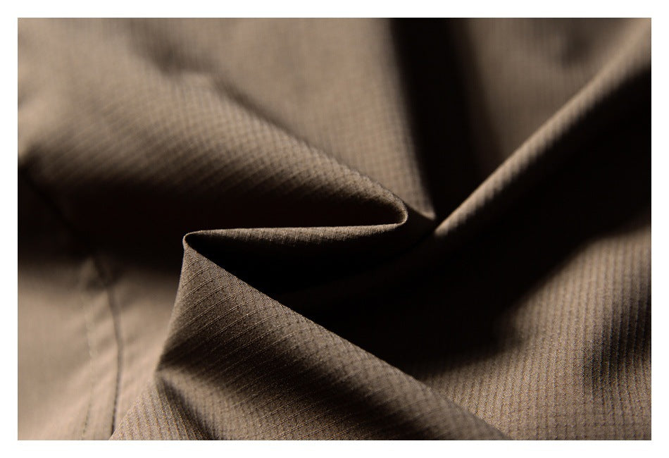 Close-up of brown garment fabric arranged in folds, showing its fine surface texture.