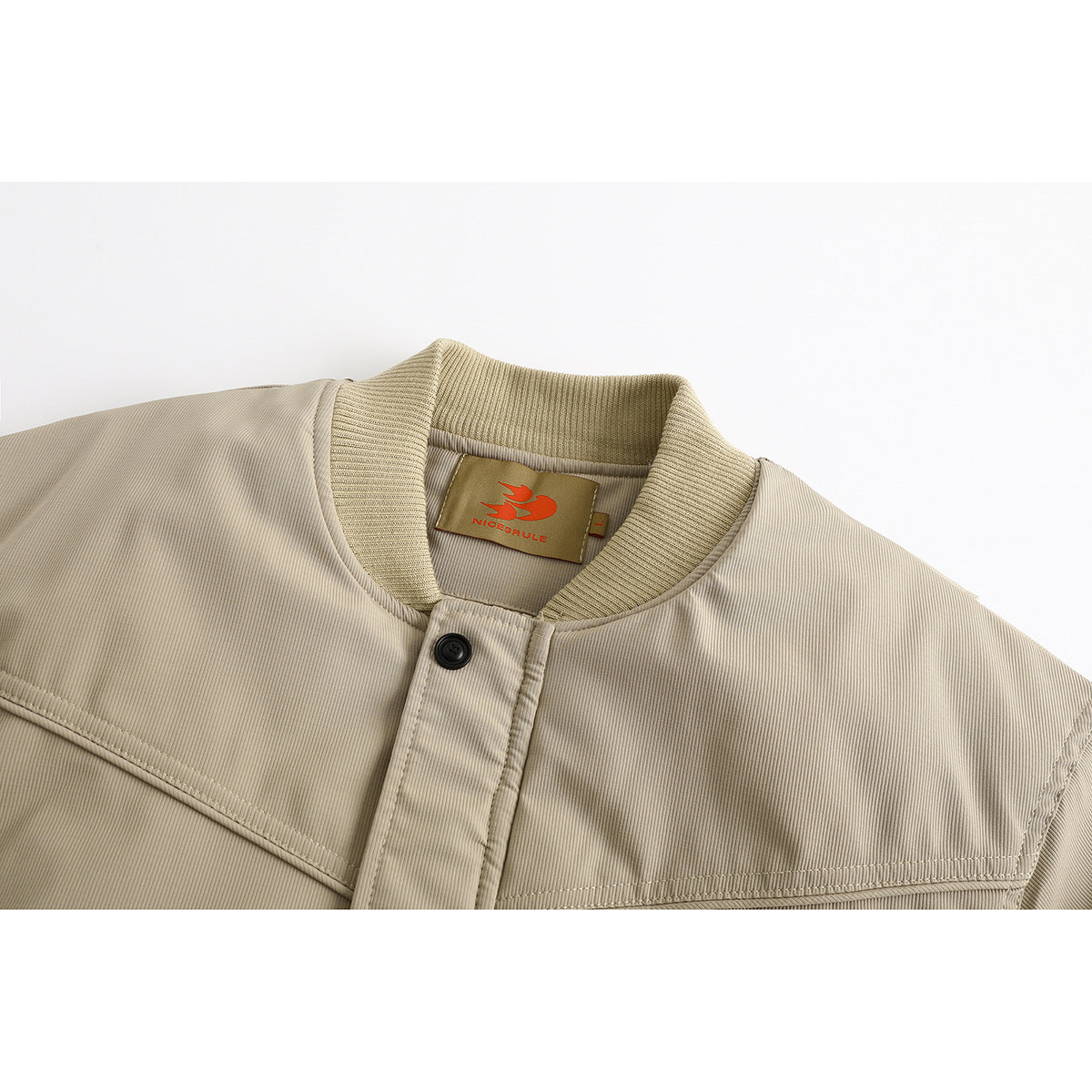 Close-up of a beige jacket's ribbed collar, button placket, stitched yoke, and neck label.