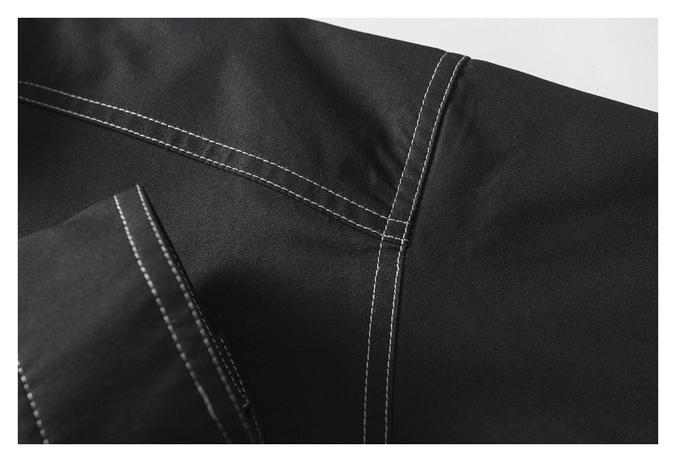Close-up of black garment panels joined by white contrast-stitched seams.