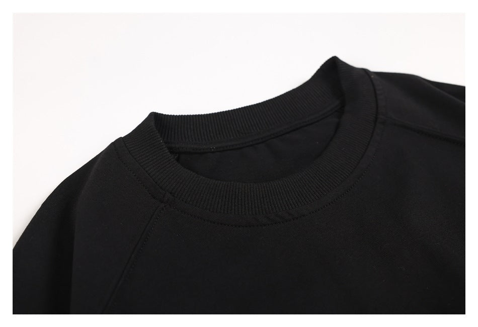 Close-up of the black sweatshirt's ribbed crew neckline and shoulder seams.