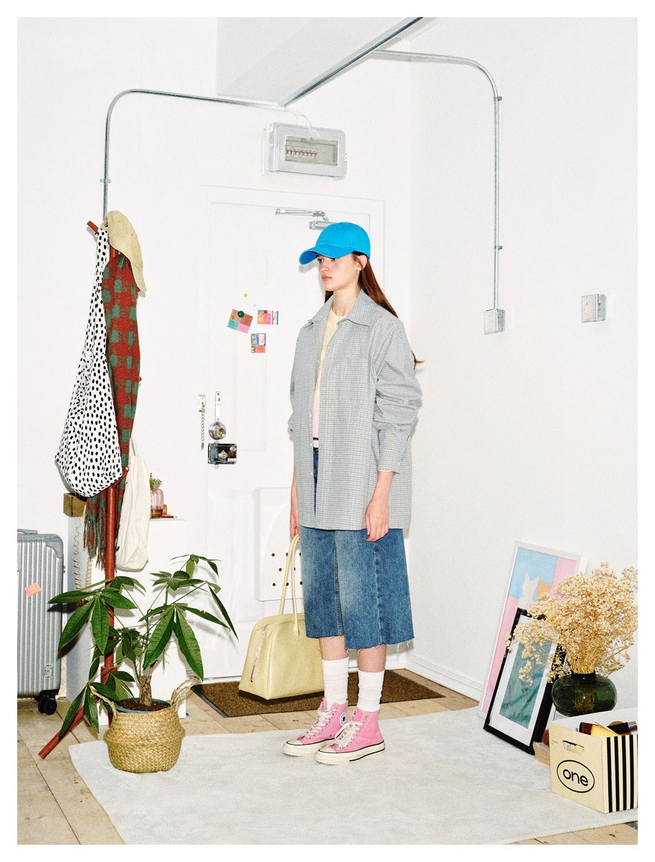 Side view of model wearing the light blue check shirt open over a tee with denim shorts and pink sneakers