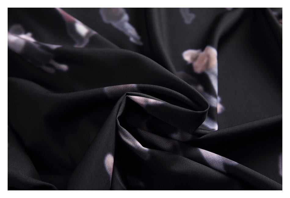 Close-up of draped black fabric with a subtle print of small pale figures.