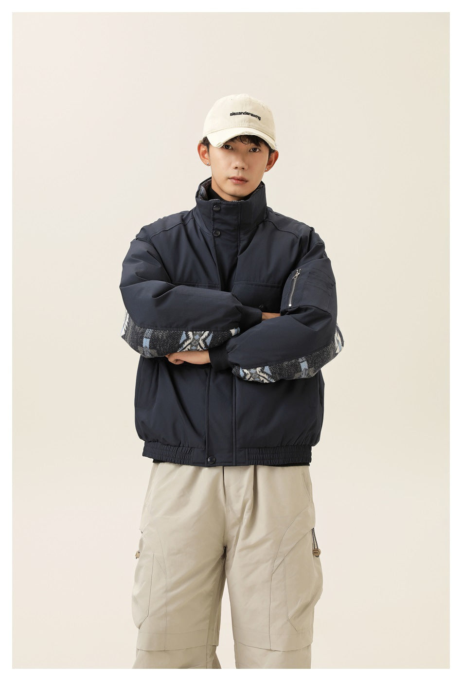 Front view of a model wearing a navy utility jacket with a high collar, snap front and patterned sleeve panels.