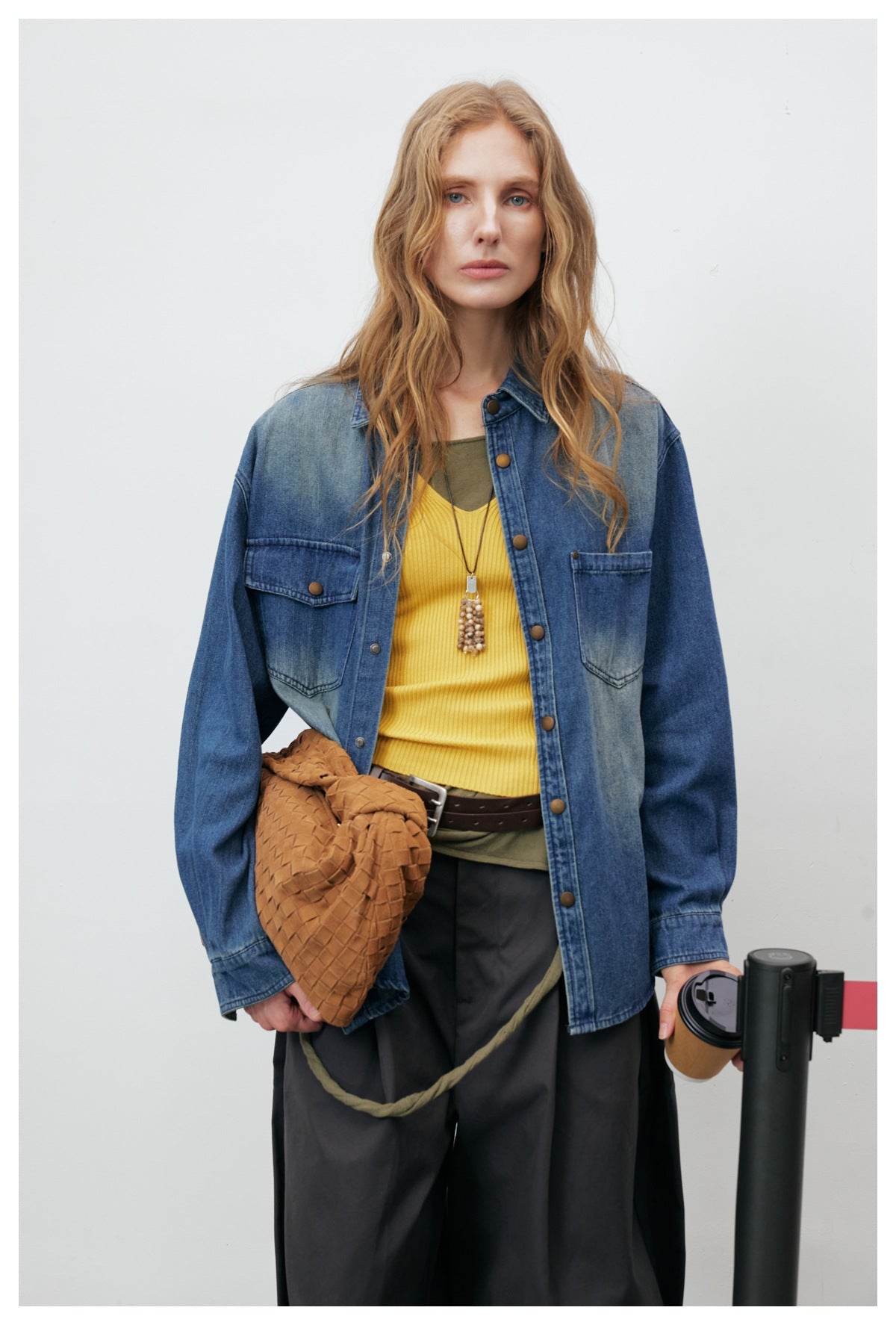 Close-up of model wearing the blue washed denim shirt-jacket open over a yellow ribbed top