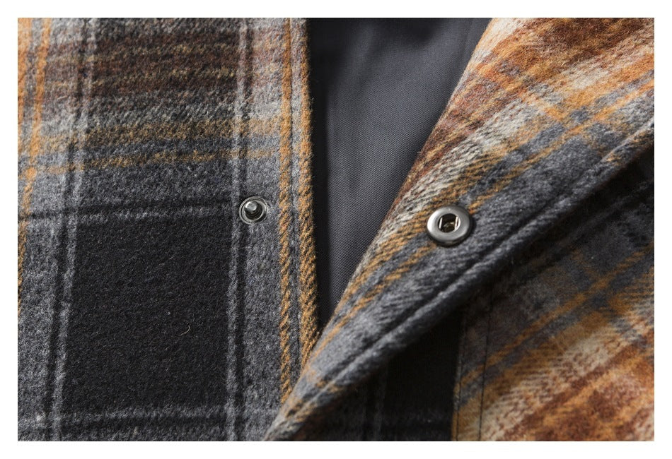 Close-up of metal snap fasteners along the front opening of a charcoal and rust plaid garment.