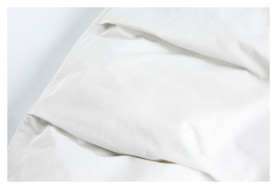 Close-up of overlapping white garment panels with stitched edges.