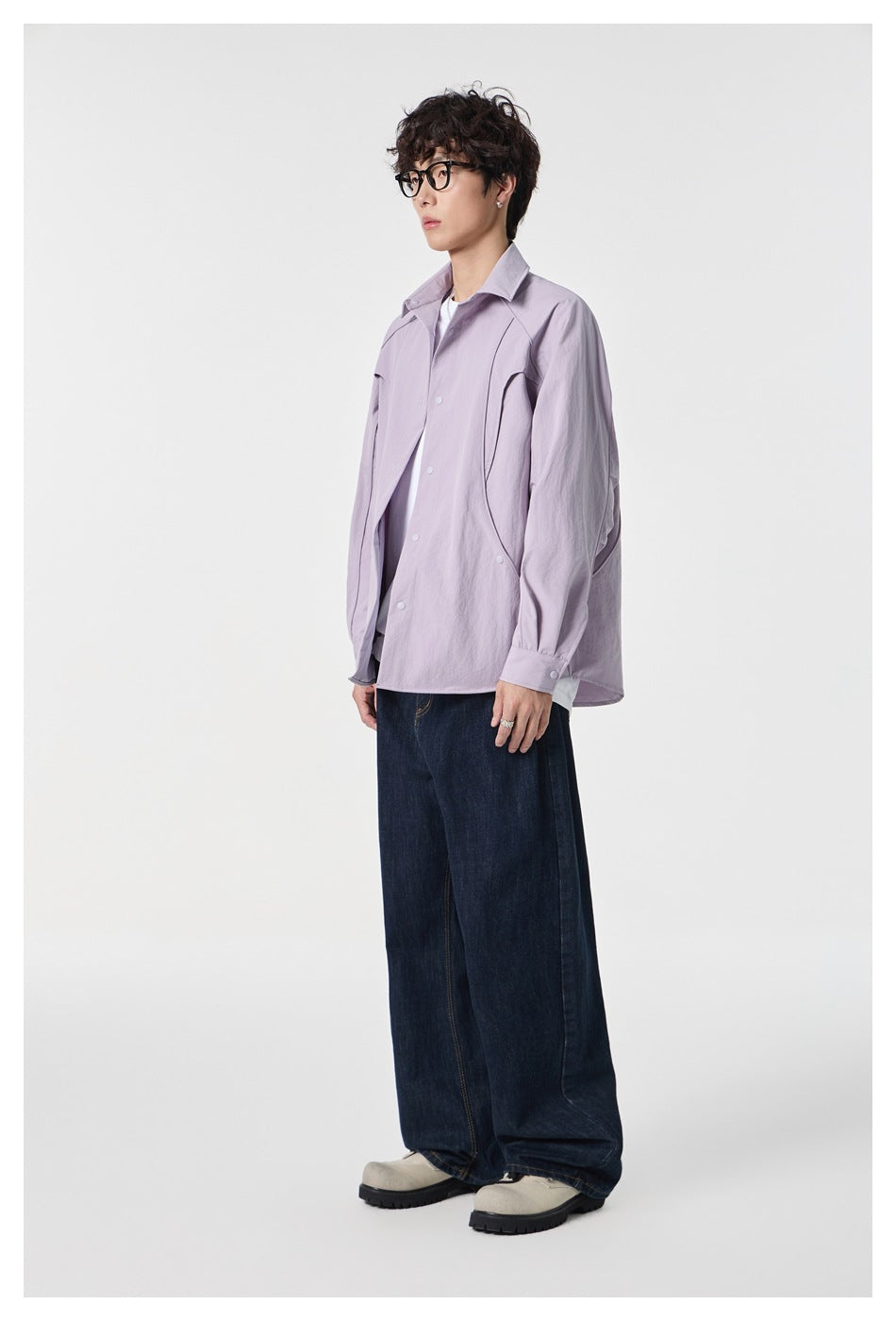Side view of a model wearing a pale lavender snap-front shirt and dark wide-leg jeans.