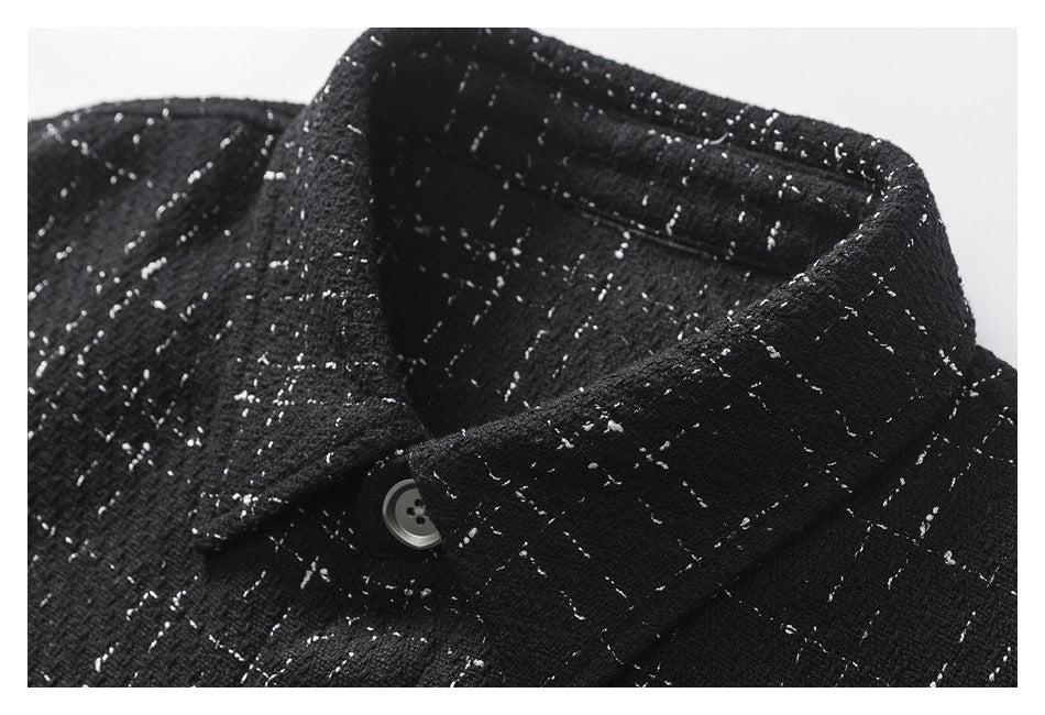 Close-up of the pointed collar and gray button on a black shirt with a scattered white fleck pattern.