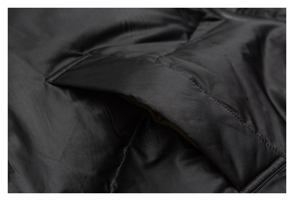 Close-up of a stitched pocket opening on black padded fabric.