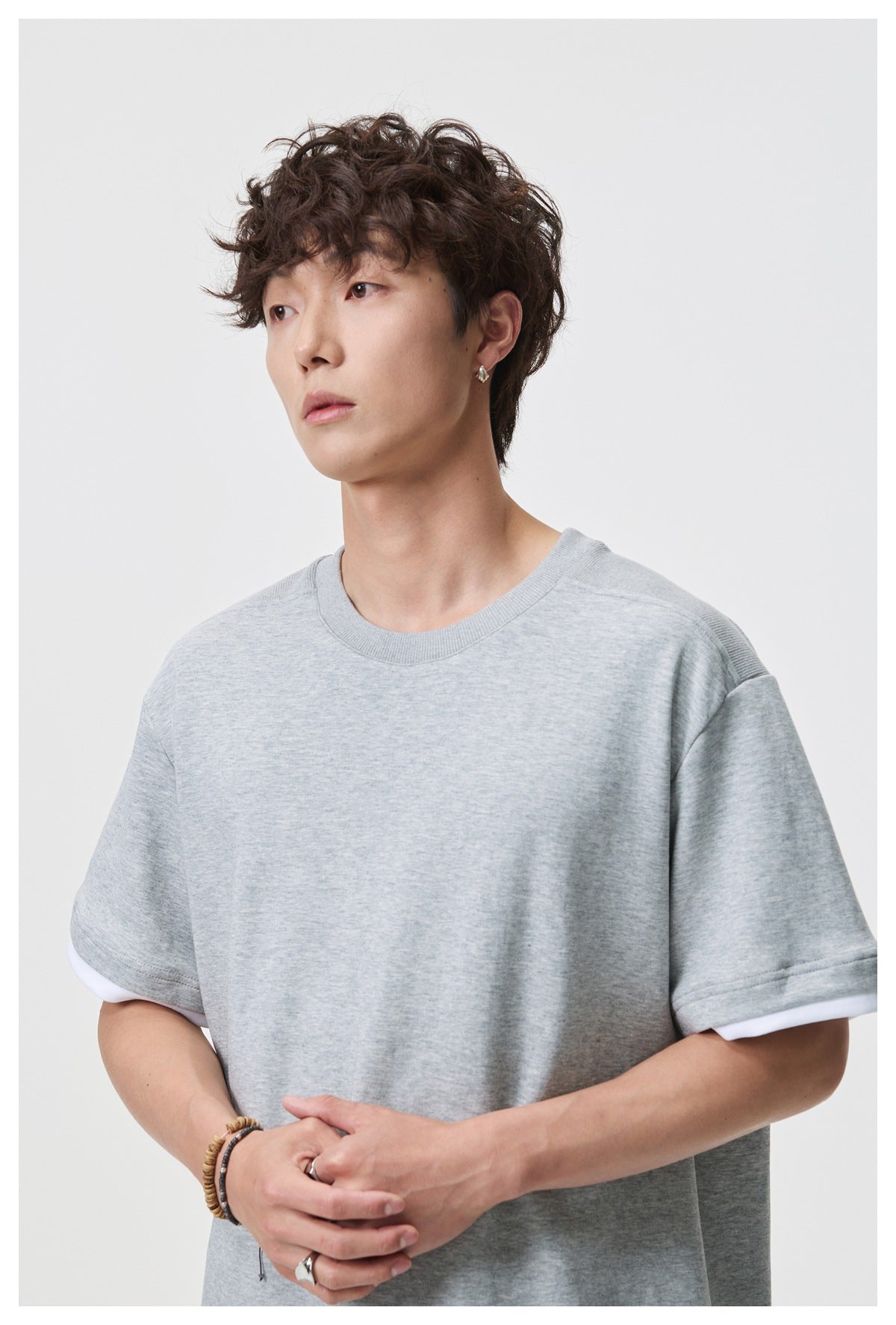 Close view of a model wearing a light gray tee with a ribbed crew neck and white under-sleeve trim.