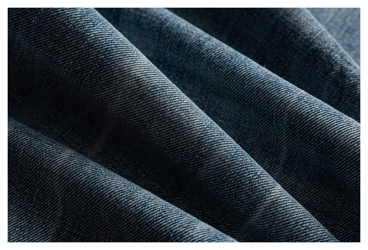 Close-up of dark blue denim fabric arranged in soft folds, showing its diagonal weave.