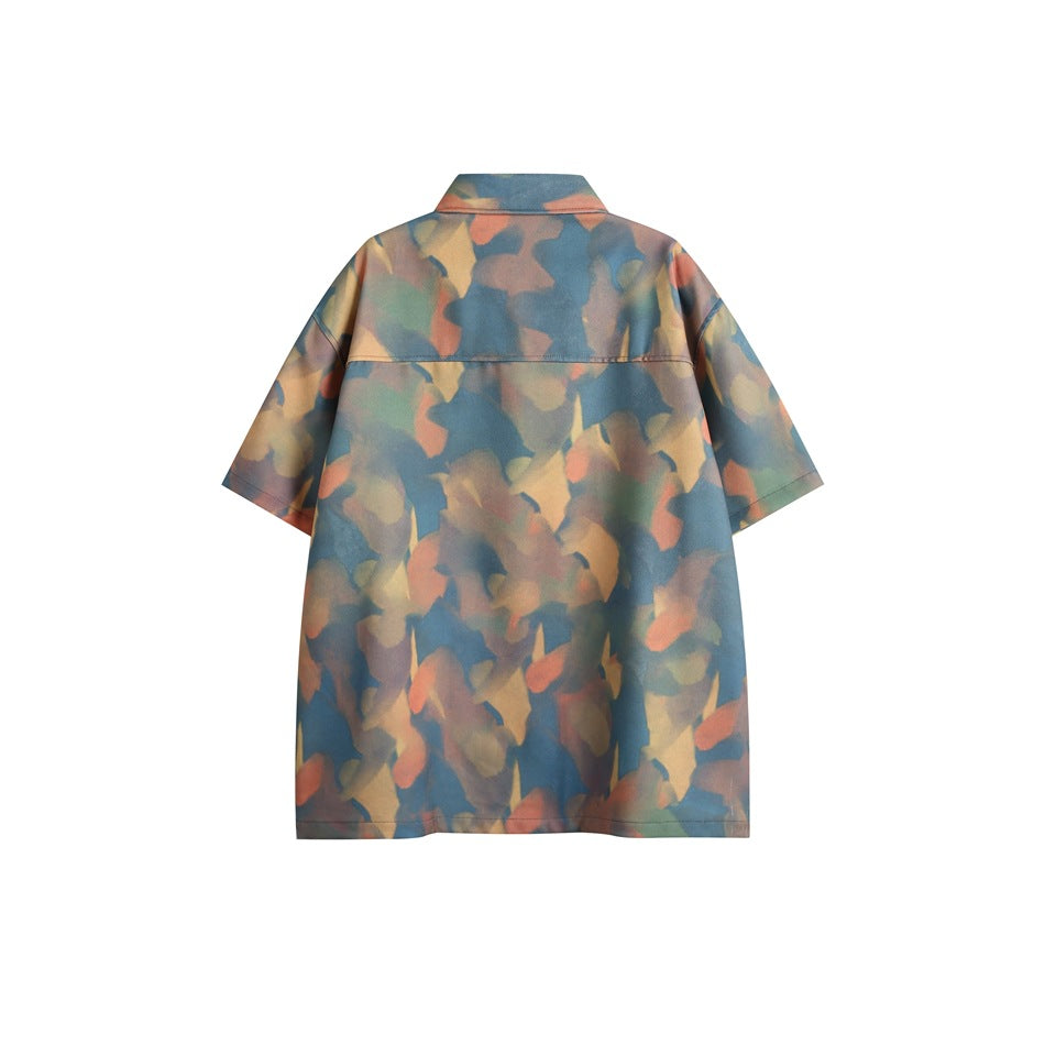 Back view of a short-sleeve button-up shirt with an all-over muted blue, brown, orange, and green abstract print.