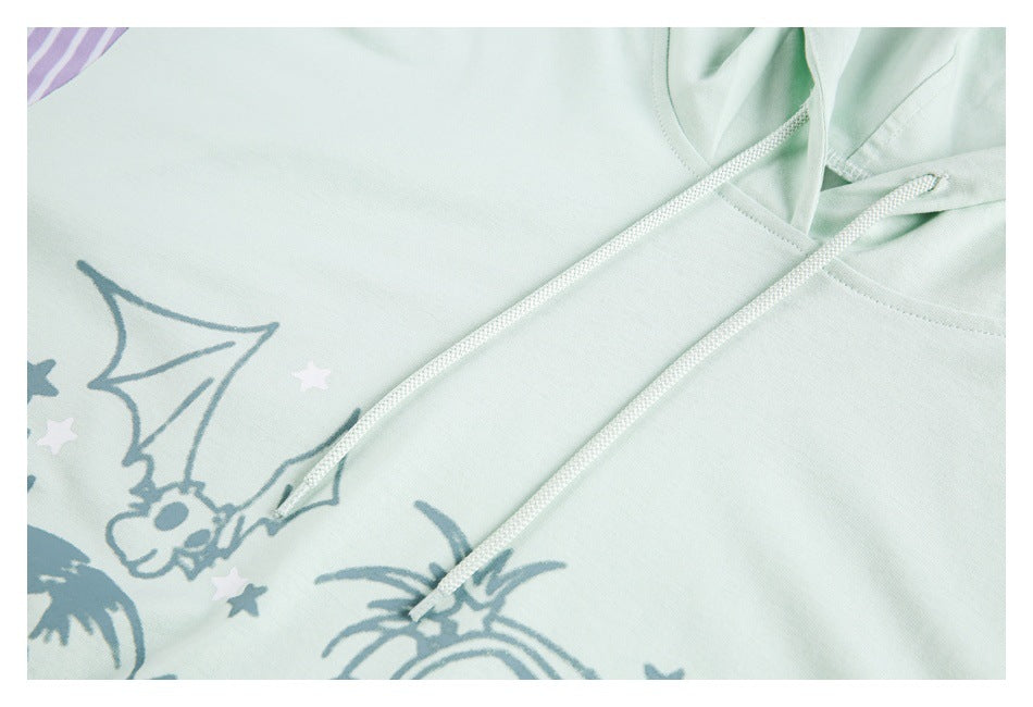 Close-up of a pale mint hoodie with white drawstrings and a blue-gray cartoon print with stars.
