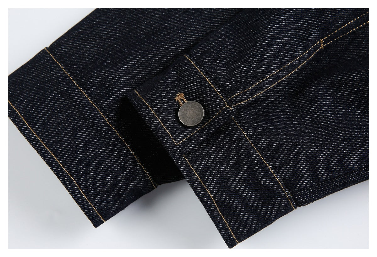 Close-up of a metal button and stitched overlapping panels on dark indigo denim.