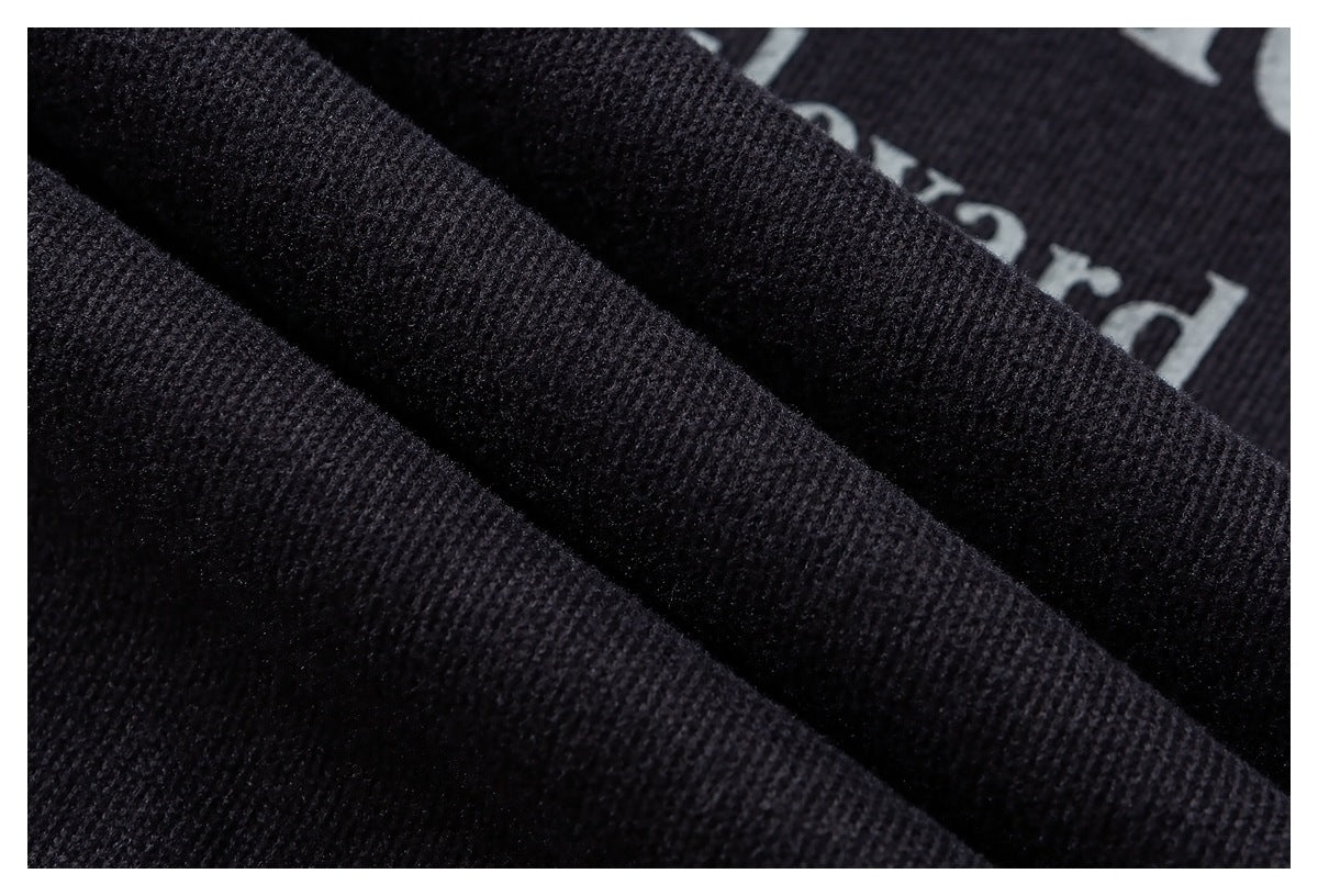 Extreme close-up of dark textured fabric folded over a partially visible white printed design.