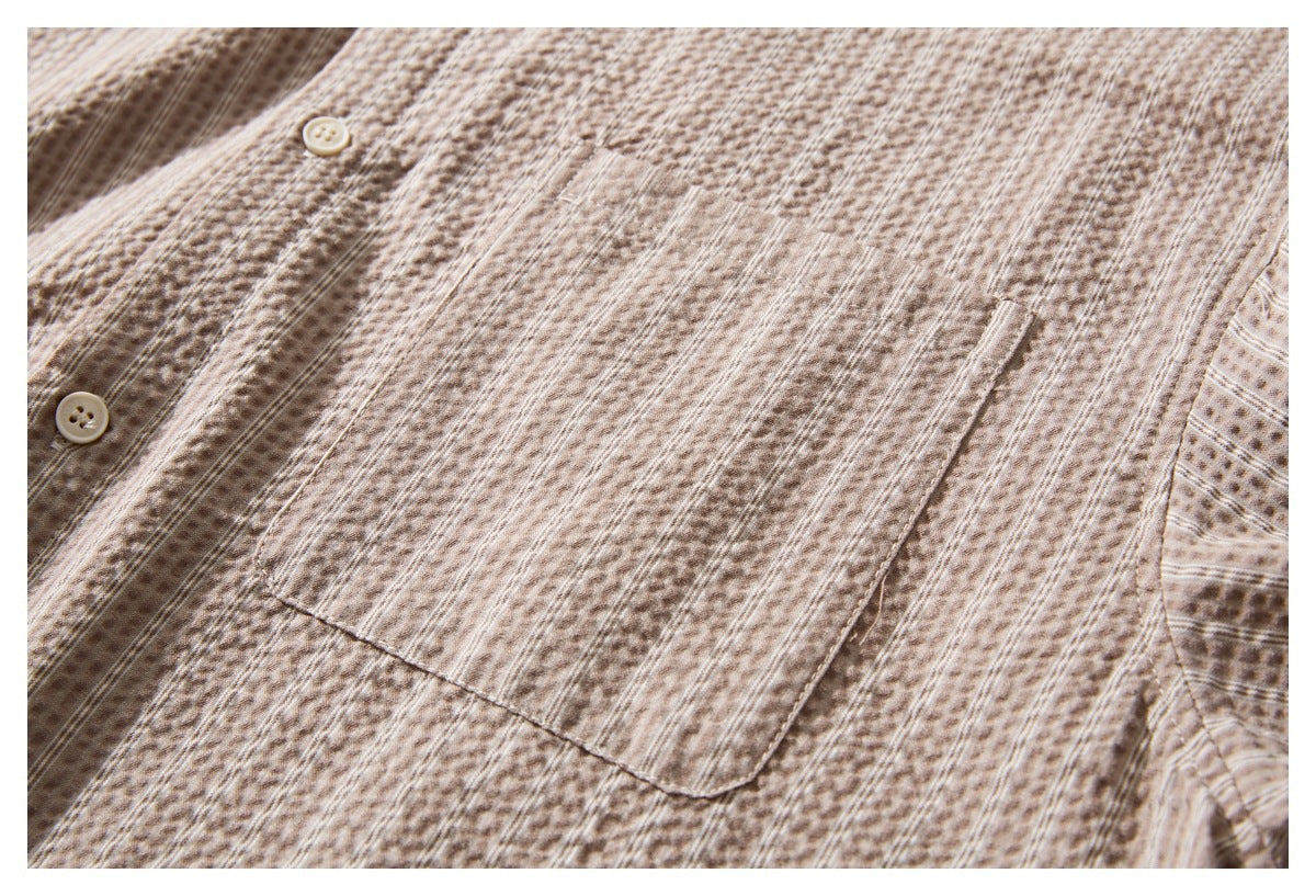 Close-up of a rectangular chest pocket and buttons on a beige-brown patterned shirt.