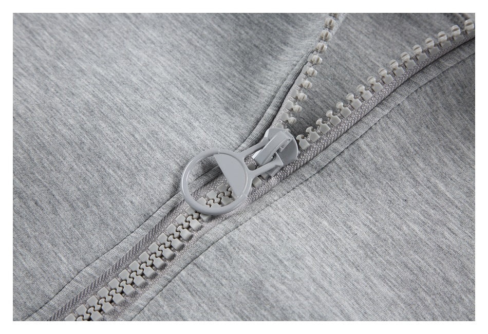 Close-up of the light gray jacket's chunky zipper and oversized round pull.