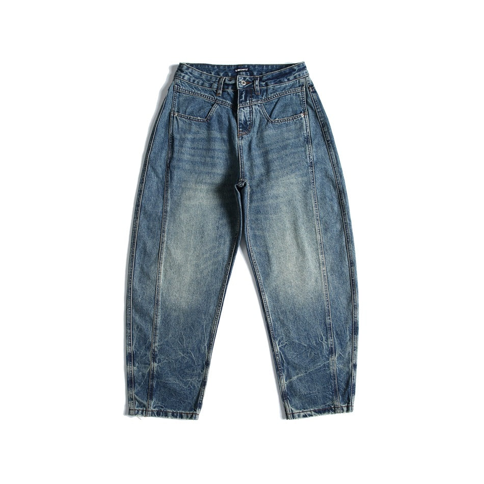 Front view of blue washed denim jeans with faded finish, front yoke seam and angled pockets, laid flat on white