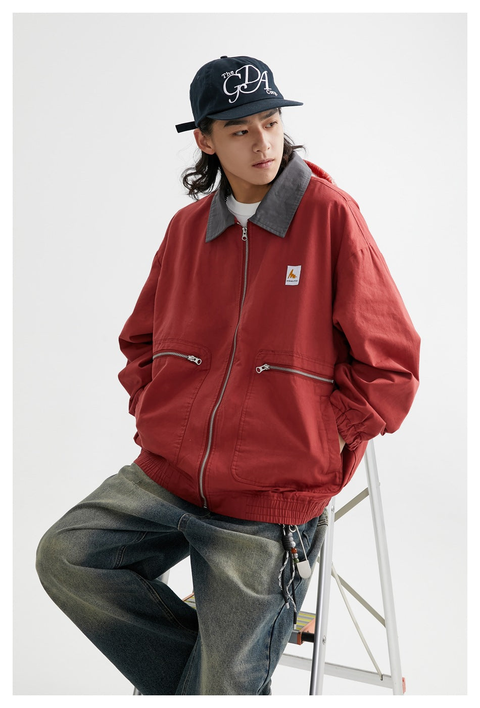 Model wearing a red zip-front jacket with a charcoal collar, elastic cuffs and hem, and zip pockets.