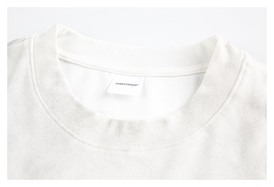 Close-up of a white T-shirt's ribbed crew neck and inner brand label.