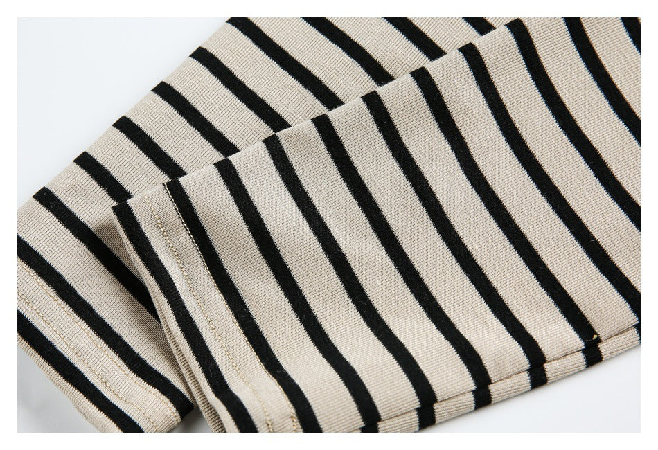 Folded beige garment with bold black stripes and stitched edges, shown close up.