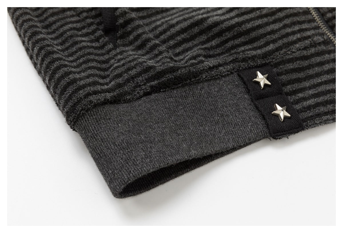 Close-up of a charcoal ribbed cuff with two silver star studs and part of a zipper.