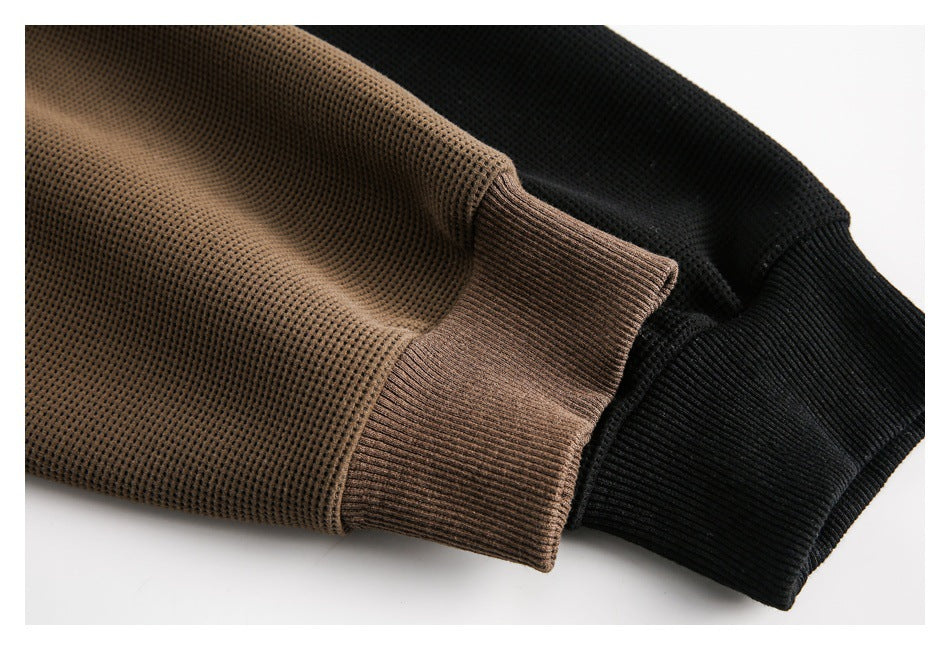 Close-up of brown and black shirt sleeves showing textured fabric and ribbed cuffs.