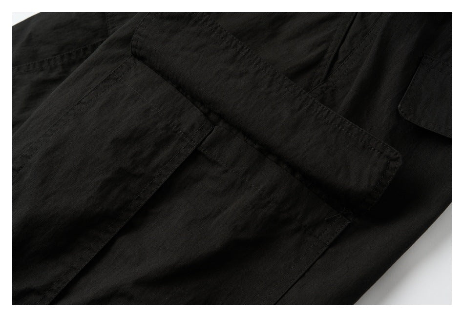 Close-up of black garment panels with overlapping flap pockets and stitched seams.
