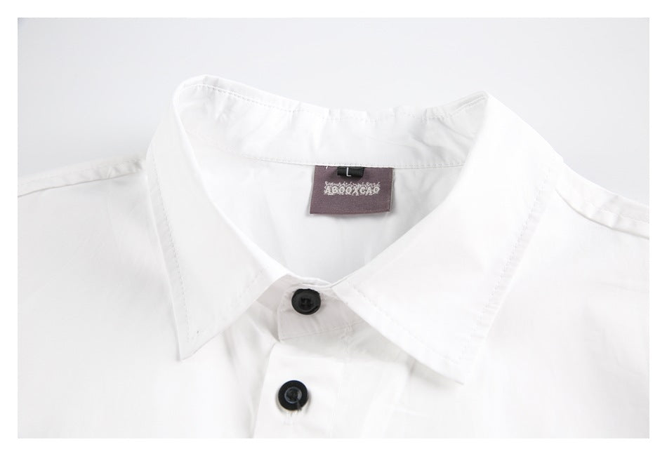 Close-up of a white shirt collar, black buttons, and sewn-in neck label.