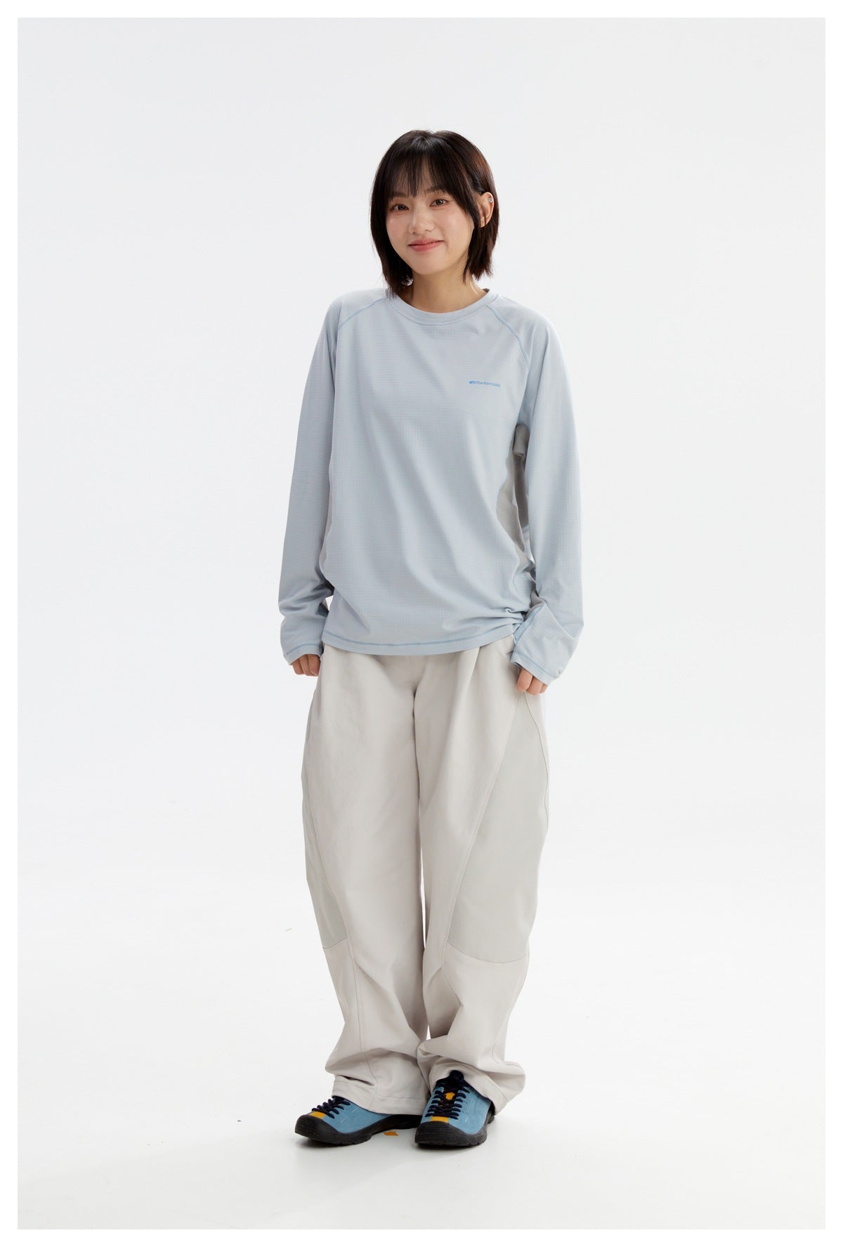 Model wearing a pale blue long-sleeve top with raglan seams and loose off-white trousers.