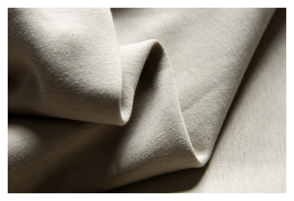 Macro view of light beige fabric draped in soft folds, showing its fine surface texture.