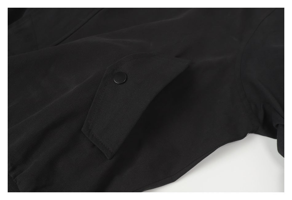 Close-up of a black jacket flap pocket with a snap button and visible stitching.