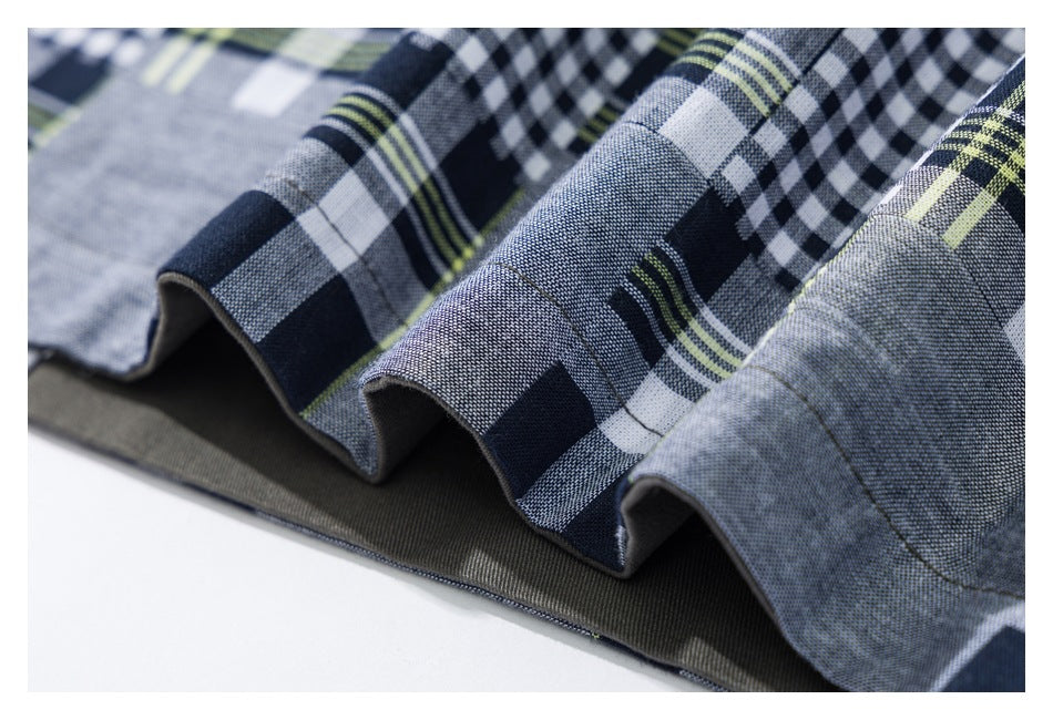 Close-up of a wavy garment hem showing multiscale gray and navy plaid fabric and a dark inner layer.