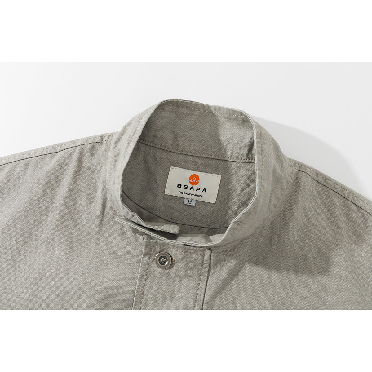 Close-up of a light gray jacket's stand collar, button placket, and sewn neck label.