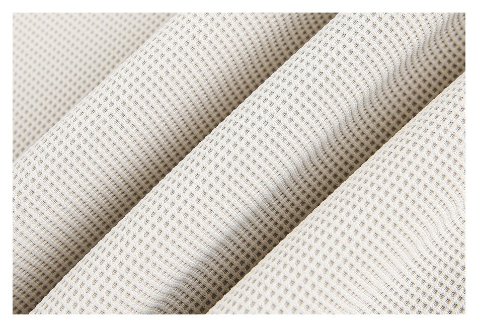 Close-up of cream fabric showing its raised repeating texture across several folds.