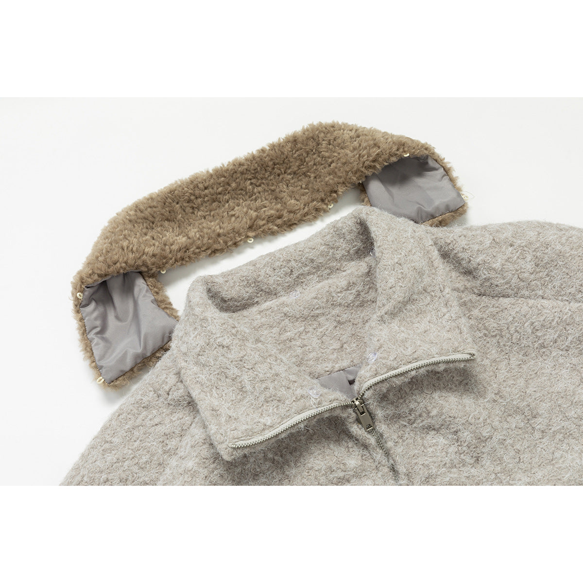 Close-up of a light beige jacket collar, showing its taupe fuzzy underside, gray lining, and front zipper.