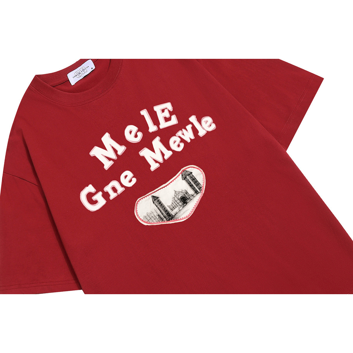 Angled flat lay of a red short-sleeve T-shirt with white chest lettering and a small illustrated patch.