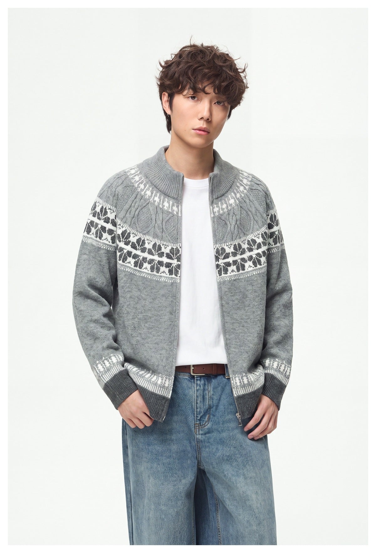 Model wearing an open light gray zip-up knit cardigan with patterned bands over a white shirt and blue jeans.