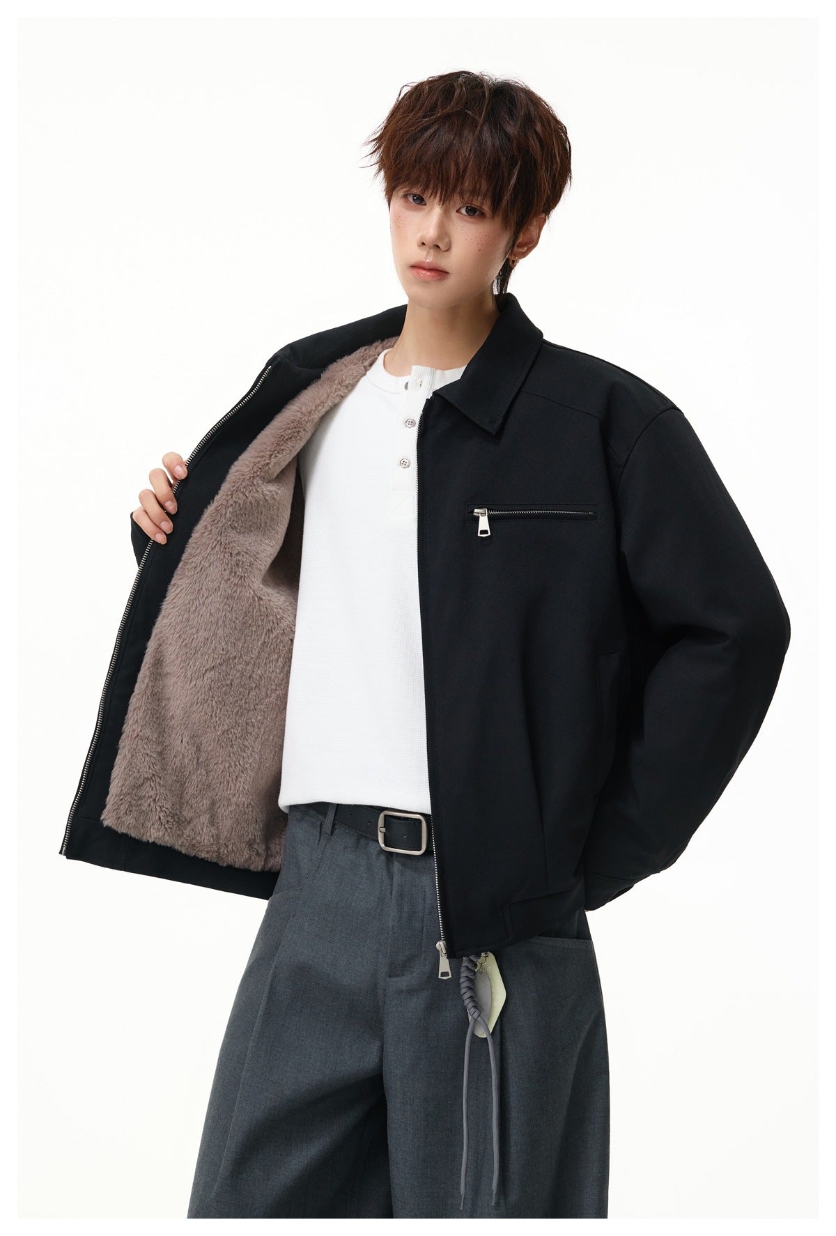 Model holding open a black zip jacket to show its taupe plush lining and chest zip pocket.