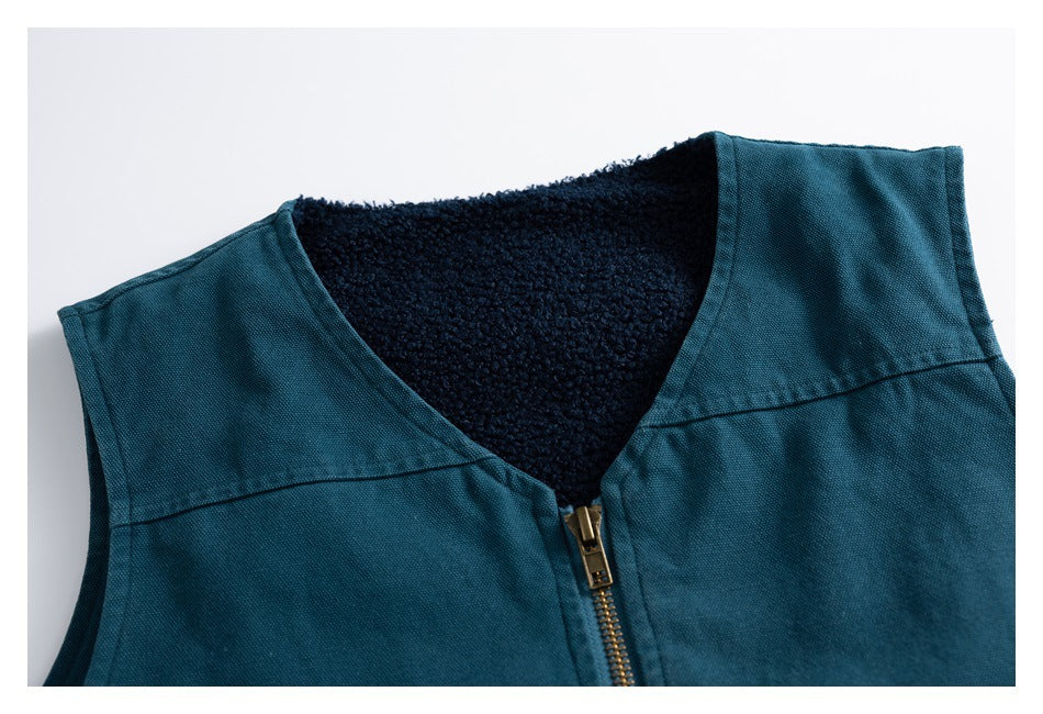 Close-up of a teal vest's V-neck, brass-tone zipper and dark textured lining.