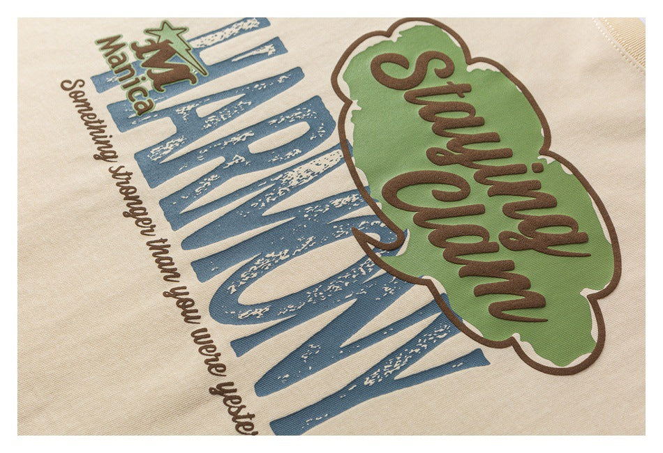 Close-up of a beige T-shirt’s colorful graphic, including a green “Staying Calm” bubble and blue lettering.