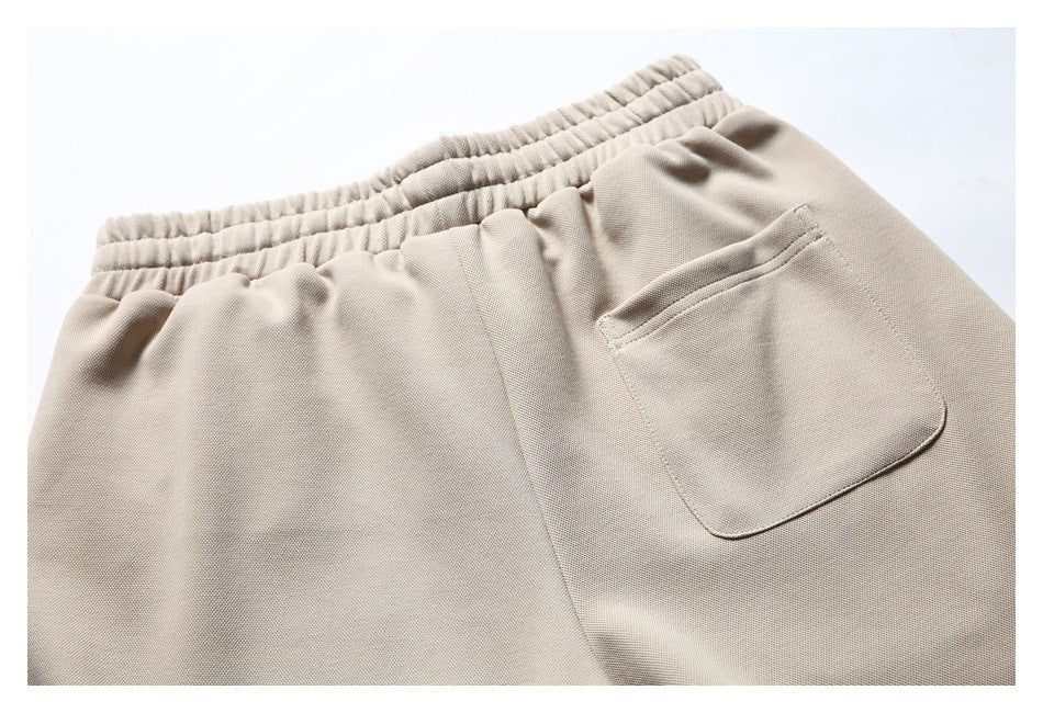 Close-up of a light beige garment's elastic waistband and patch pocket.